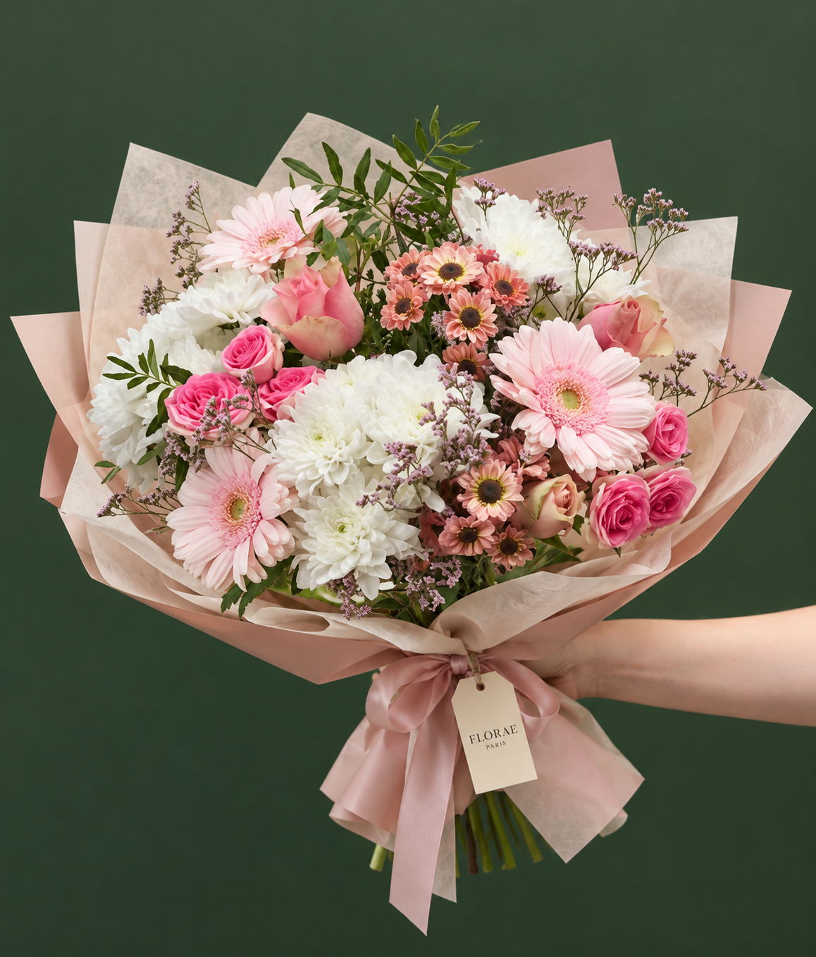 Éveil Rosé — Roses roses, gerberas rose pâle, chrysanthèmes blancs et saumon, petites fleurs mauves et feuillage. Bouquet Florae sur fond vert.