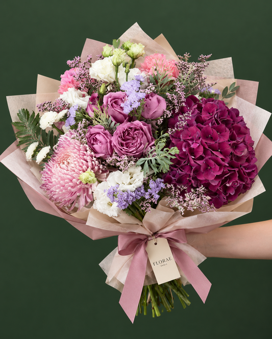 Velours Améthyste — Hortensia pourpre, roses mauves, lisianthus blancs, chrysanthème rose, œillets et petites fleurs mauves. Bouquet Florae sur fond vert.